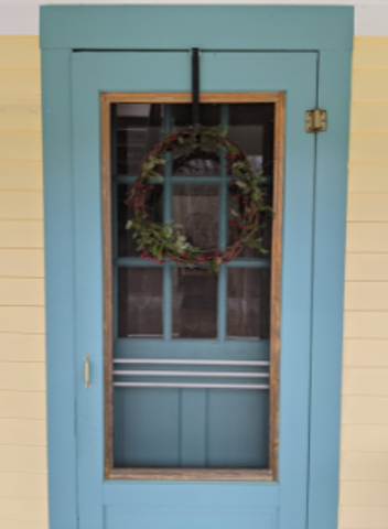 Green wreath behind blue storm door