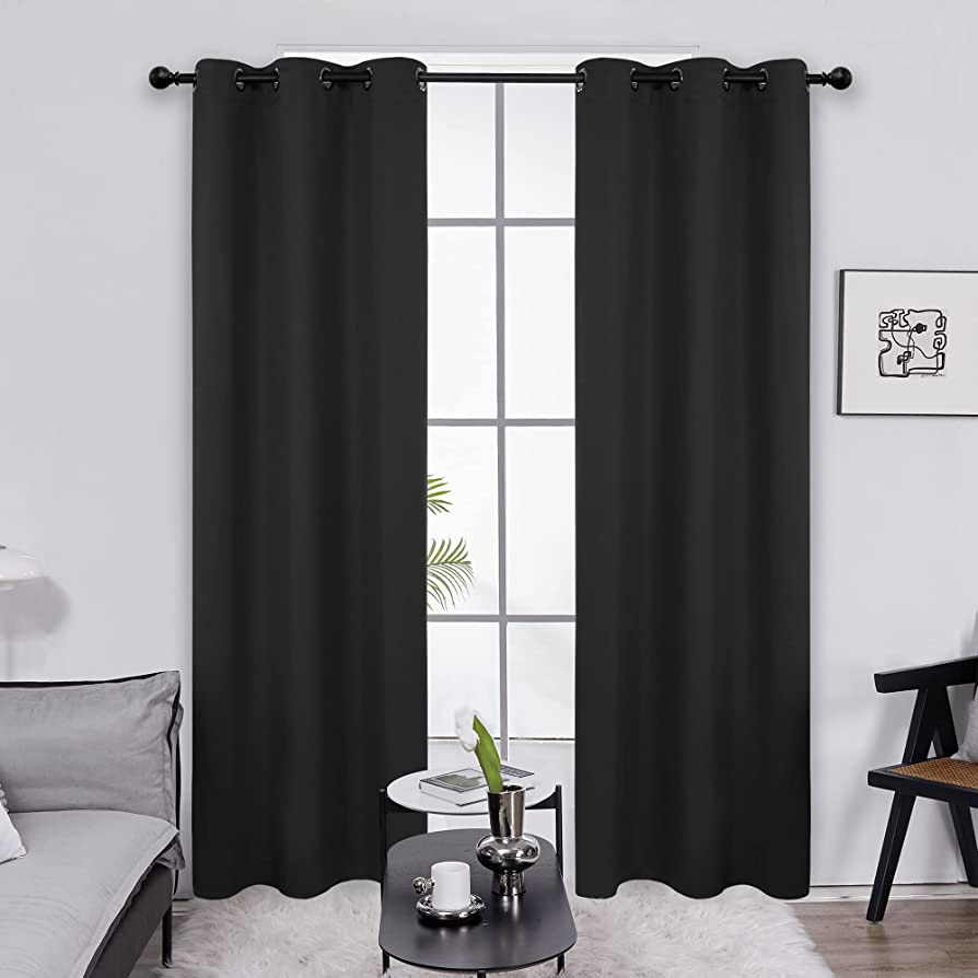 Blackout curtains displayed in living room in front of table. 